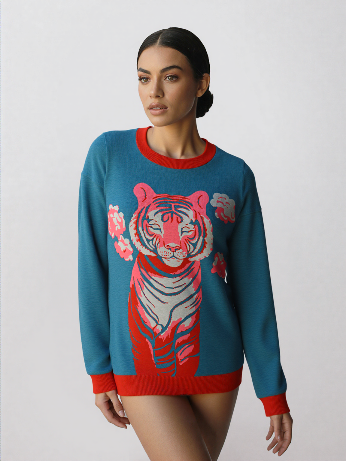 Woman wearing a blue sweater with a pink tiger design on a white background