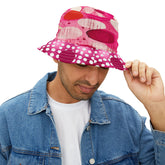 Person wearing a pink polka dot and red and pink abstract circle design bucket hat with a denim jacket and white shirt on a white background