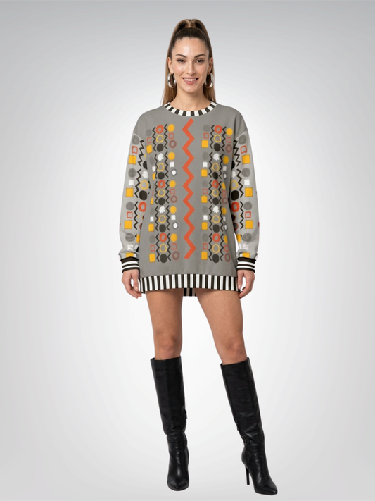 A woman modeling a gray long-sleeve sweatshirt worn as a mini dress with colorful geometric patterns and black striped trim, paired with black knee-high boots, against a light gray studio background.